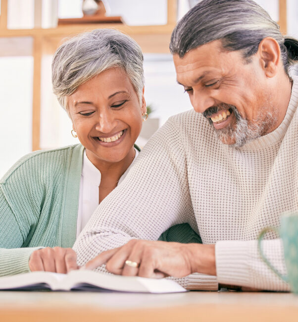 a couple of older adults happily reading a book together