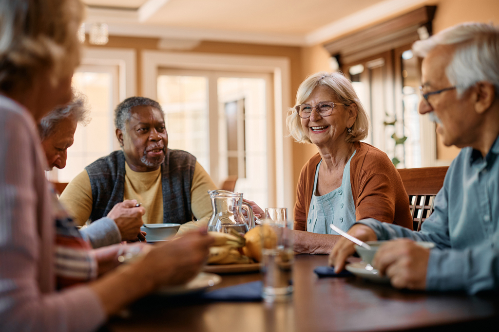 a group of seniors sitting around a table, having a good time together