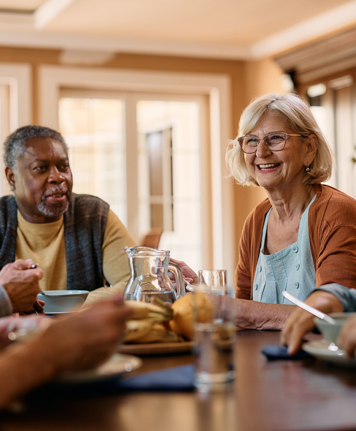 a group of seniors sitting around a table, having a good time together