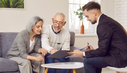 Senior couple reviewing documents with a young advisor at home, smiling and engaged in a discussion.