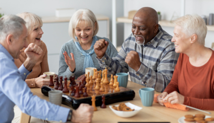 A group of seniors sitting around a table playing chess.