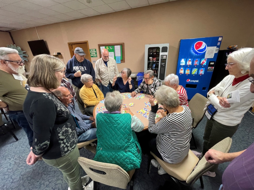 Seniors playing cards gathered around a table.