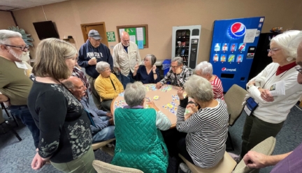 Seniors playing cards gathered around a table.